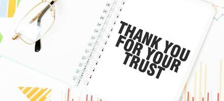 Text danken Sie zum Ihre Vertrauen. auf Weiß Notizblock, Gläser, Grafiken und Diagramme. foto