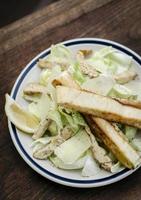 einfacher gesunder Bio-Hähnchen-Caesar-Salat auf Holztisch foto