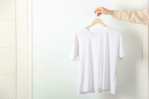 Weiß T-Shirt Attrappe, Lehrmodell, Simulation im Frau Hand. Bella Segeltuch spotten oben im minimal Stil. foto
