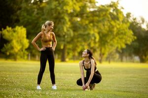 zwei ziemlich jung Frauen Dehnen im das Park foto