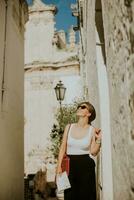 weiblich Tourist mit Papier Stadt Karte auf eng Straßen von Ostuni, Italien foto