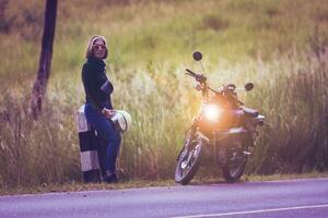 ziemlich Frau halten Sicherheit Helm Stehen auf lokal Straße neben klein Enduro Motorrad foto