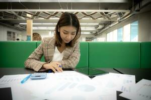 schön asiatisch Geschäft Frau Sitzung und Arbeiten mit Glück auf ihr Schreibtisch. foto