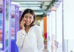 schön asiatisch Geschäft Frau ist Stehen und reden auf das Telefon mit ein glücklich lächeln, Digital Marketing. foto