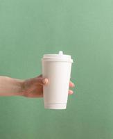 weiße große Papierkaffeetassen zum Mitnehmen auf grünem Hintergrund