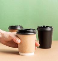 Schwarze Papierkaffeetassen zum Mitnehmen verspotten auf grünem und braunem Hintergrund foto
