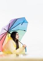 nachdenkliche Frau, die draußen steht und einen regenbogenfarbenen Regenschirm hält foto