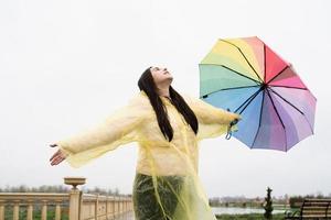 Frau mit Regenschirm, die in den Regentropfen fängt und den Regen genießt foto