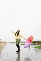 Frau mit Regenschirm, die in den Regentropfen fängt und den Regen genießt foto