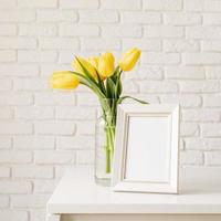 gelbe Tulpen in einer Glasvase und einem leeren Bilderrahmen foto