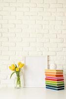 gelbe Tulpen in einer Glasvase und einem leeren Bilderrahmen