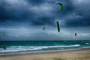 Sommer- Landschaft mit das Ozean mit dunkel wolkig Wellen und surfermi Kit mit Fallschirme schwebend auf das Ufer foto