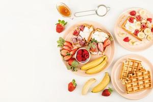 Waffeln mit Früchten und Beeren, Sahne und Honig in einem Teller foto