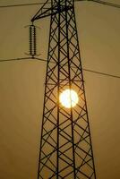 ein Silhouette von ein Elektrizität Turm mit das Sonne im das Hintergrund foto
