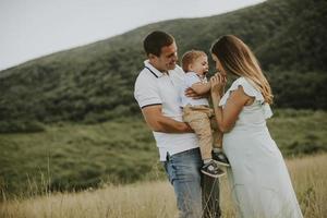 junge Familie mit süßem kleinen Jungen, der Spaß im Freien auf dem Feld hat foto