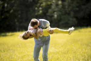 Vater mit Tochter, die Spaß auf dem Gras im Park hat foto