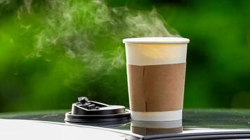 Kaffee wegbringen im ein Papier Tasse auf oben von das Auto Dach Grün Baum Hintergrund beim Sonnenaufgang im das Morgen, selektiv Fokus, Sanft Fokus. foto