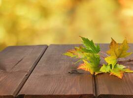 Herbst Gelb Blätter auf hölzern Tabelle auf Herbst verschwommen Hintergrund foto