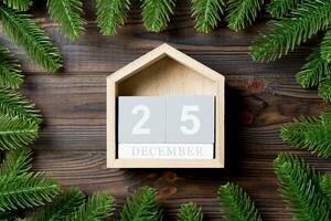 Blick von oben auf den Kalender, der mit einem Rahmen aus Tannenbaum auf Holzhintergrund dekoriert ist. der fünfundzwanzigste dezember. Weihnachtszeit-Konzept foto