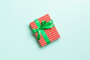 eingewickelt Weihnachten oder andere Urlaub handgemacht Geschenk im Papier mit Grün Band auf Blau Hintergrund. Geschenk Kasten, Dekoration von Geschenk auf farbig Tisch, oben Aussicht mit Kopieren Raum foto