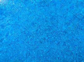 Oberfläche von Blau Schwimmen Schwimmbad Unterseite Ätzmittel Welligkeit und fließen mit Wellen Hintergrund. hell Blau zerrissen Wasser im Schwimmen Schwimmbad, Sommer- Hintergrund. Textur von Wasser Oberfläche. oben Sicht. foto