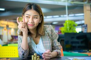 schön asiatisch Geschäft Frau halten ein Münze im einer Hand mit ein foto