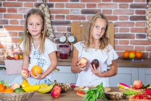 zwei wenig Mädchen im das Küche mit frisch Gemüse. gesund Essen Konzept.. glücklich Schwestern foto