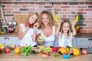 Mutter und Töchter Kochen zusammen im das Küche. gesund Essen Konzept. Porträt von glücklich Familie mit frisch Smoothies. foto