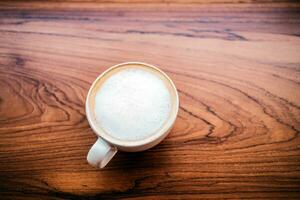 oben Aussicht von ein Tasse von Cappuccino Kaffee auf hölzern Tabelle foto