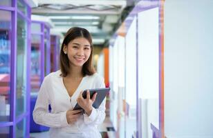 schön asiatisch Geschäft Frau ist Stehen gegenüber das Kamera während selbstbewusst halten ein Tablette und lächelnd, Kopieren Raum, Digital Marketing. foto