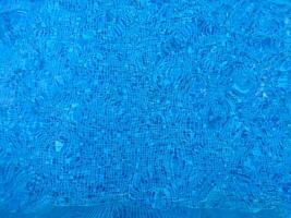 Oberfläche von Blau Schwimmen Schwimmbad Unterseite Ätzmittel Welligkeit und fließen mit Wellen Hintergrund. hell Blau zerrissen Wasser im Schwimmen Schwimmbad, Sommer- Hintergrund. Textur von Wasser Oberfläche. oben Sicht. foto