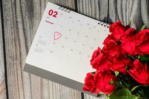 oben Sicht, Symbol Herz Kennzeichen Tag 14 .. mit Rosa. Kalender von Februar mit verschwommen Rose Blume auf das Weiß Schreibtisch, das Konzept zum Valentinstag Tag auf 14 .. Februar 2021. Nahaufnahme, und selektiv Fokus. foto