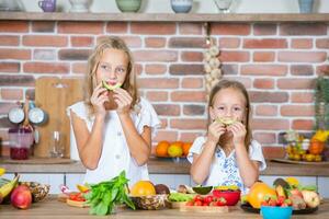 zwei wenig Mädchen im das Küche mit frisch Gemüse. gesund Essen Konzept. glücklich Schwestern. foto