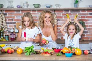 Mutter und Töchter Kochen zusammen im das Küche. gesund Essen Konzept. Porträt von glücklich Familie mit frisch Smoothies. foto
