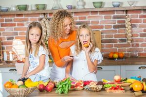 Mutter und Töchter Kochen zusammen im das Küche. gesund Essen Konzept. Porträt von glücklich Familie mit frisch Smoothies. glücklich Schwestern. foto