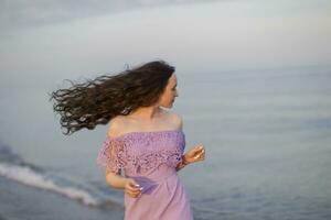 schön jung Mädchen auf das Hintergrund von das Meer mit lange fließend Haar foto