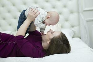 Mama mit ihr wenig Sohn auf das Bett.Mutter und Baby foto