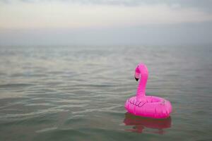 Rosa Flamingo aufblasbar auf das Hintergrund von das Meer foto