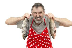 reifen Fischhändler im rot Schürze halten groß frisches Wasser Fisch und suchen beim Kamera auf Weiß Hintergrund foto