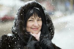 Alten Frau im ein Pelz Kapuze bedeckt mit Schnee foto