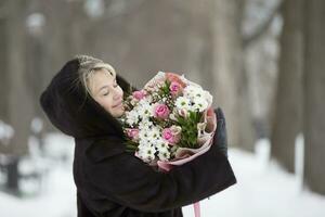 glücklich Frau mit ein Strauß von Blumen auf ein Winter Hintergrund foto