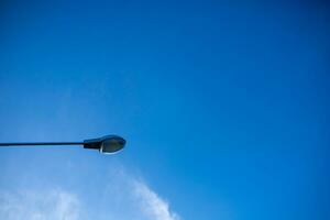 elektrisch Licht Birne auf das Seite von das Straße über ist das Blau Himmel. foto
