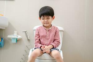 asiatisch Junge Sitzung auf das Toilette Schüssel im Hand halten Gewebe foto