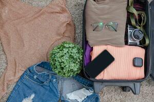 Anordnung von Kleider und Zubehör im ein Koffer, Reisen Konzept. foto