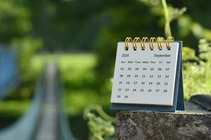 September 2024 Kalender mit Grün verschwommen Hintergrund von hängend Brücke. foto