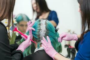 Prozess von Haar Farbstoff im Schönheit Salon. Friseure bewirbt sich Farbe zu Haar während Bleichen Haar Wurzeln foto