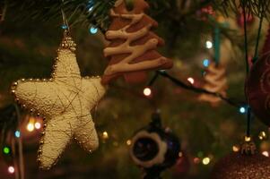 Neu Jahre Spielzeuge auf das Weihnachten Baum. Weihnachten Baum Dekorationen Nahansicht. Girlanden, Sterne und Lebkuchen auf ein Grün Kiefer. Weihnachten Atmosphäre beim heim, Hintergrund zum Urlaub Karten foto