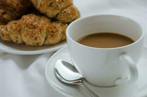 Tasse von Kaffee und Sesam Croissant zum Frühstück foto