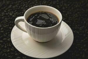 schwarz Kaffee im Weiß Tasse isoliert auf Hintergrund von geröstet Kaffee Bohnen. foto