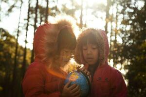 Zwei süße asiatische Mädchen lernen ein Modell der Welt auf Naturhintergrund und warmem Sonnenlicht im Park. Kinder lernen durch pädagogische Spielaktivitäten. Tag der Erde. Weltumwelttag. foto